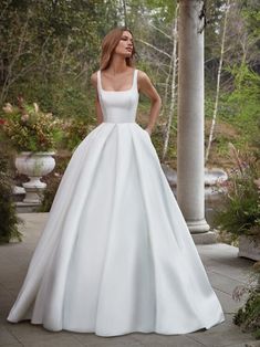 a woman in a white wedding dress posing for the camera with her hands on her hips