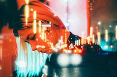 a woman standing in front of a city street at night with her head turned to the side