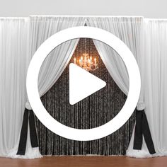 a room with curtains and a white curtain on the wall that has a video play button in front of it