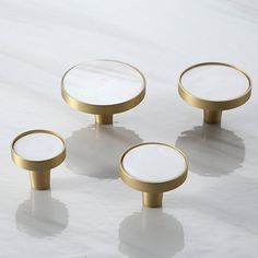 four brass knobs with white glass tops on a plain surface, all in the same pattern