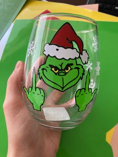 a person holding up a glass with the grin face on it