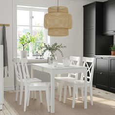 a white table and chairs in a room with black cupboards on either side of the window