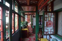 a long hallway with red and white walls, green trimmings and lots of potted plants