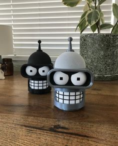 two black and white objects sitting on top of a wooden table next to a potted plant