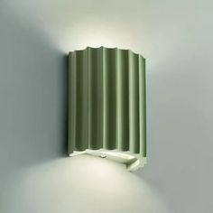 a green wall light mounted to the side of a white wall