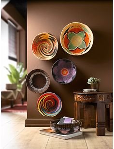 several baskets are hanging on the wall above a small table with a plant in it