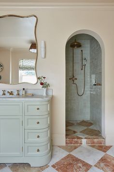 a bathroom with an oval mirror and marble counter top, along with a walk in shower