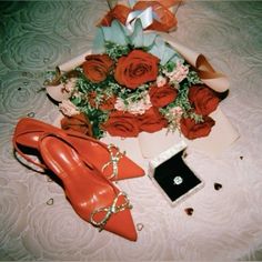 a bouquet of roses, shoes and jewelry on a bed