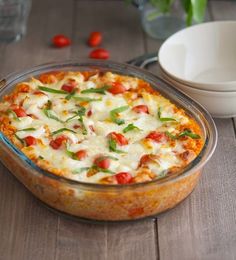 a casserole dish with tomatoes, cheese and green peppers in it on a wooden table