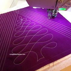 a close up of a sewing machine on a table with a purple background and white stitching