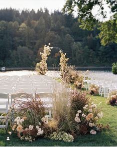 an outdoor ceremony setup with white chairs and flowers