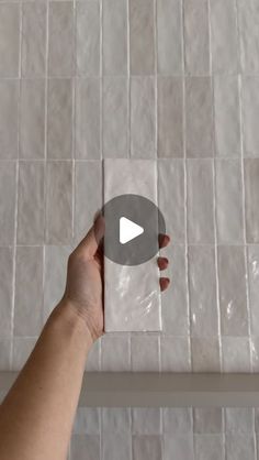 a person is holding up a white tile wall