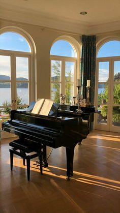 there is a piano in the middle of this living room with windows looking out onto the water