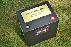 an electronic device sitting in the grass with a sign on it's back side