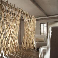 a living room filled with white furniture and wooden sticks on the wall next to a window