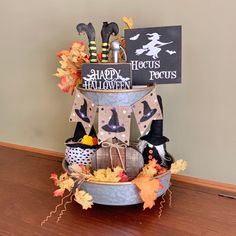 a metal bucket filled with halloween decorations on top of a wooden floor next to a sign