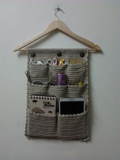 a wooden hanger with some items hanging from it's sides and a cell phone in the pocket