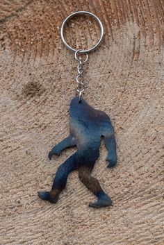 a metal keychain with a blue monkey on it's side hanging from a chain