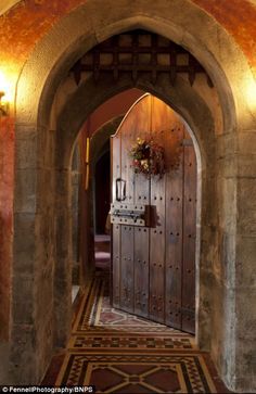 an arched wooden door leading into a hallway