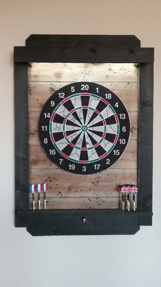 a dart board mounted to the side of a wall with darts in front of it