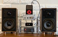 two speakers sitting next to each other on top of a wooden table with an ipod