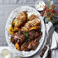 a white plate topped with meat and vegetables on top of a table next to utensils