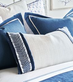 two blue and white pillows sitting on top of a bed next to eachother