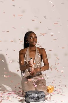 a woman sitting on the ground with confetti in front of her and holding a bottle