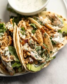 two chicken tacos on a plate with ranch dressing