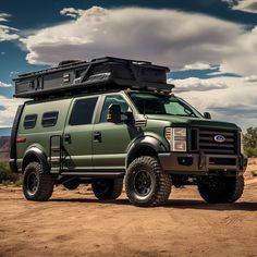 a large green truck parked on top of a dirt field