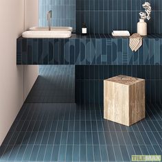 a blue tiled bathroom with a wooden stool in the middle and two sinks on either side