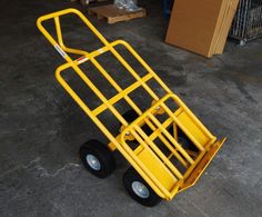 a yellow hand truck sitting on top of a cement floor next to boxes and pallets