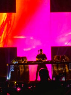 a man standing on top of a stage next to a dj's set up