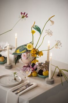 the table is set with flowers, candles and plates for dinner guests to sit at