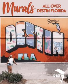 a woman is standing in front of a wall that has been painted with the word miami