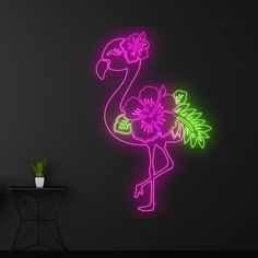 a neon pink flamingo standing on its hind legs in front of a black wall