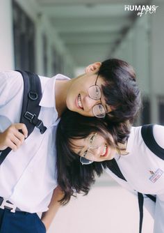 two people standing next to each other with backpacks on their backs and one person wearing glasses