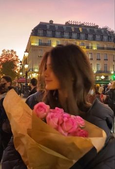 a woman holding a bunch of pink roses