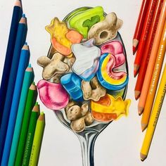 colored pencils and crayons next to a drawing of a spoon full of candy