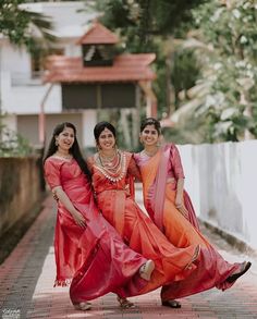 three women in red and orange dresses posing for the camera