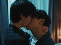 two people kissing each other in front of a window