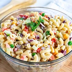 a bowl filled with macaroni salad on top of a wooden table