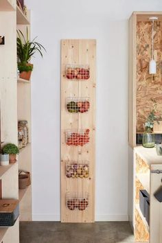 a wooden shelf with baskets hanging on it in a kitchen next to a wall mounted potted plant