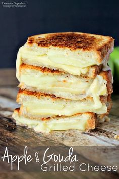 four grilled cheese sandwiches stacked on top of each other with apples in the background