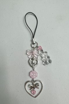 a keychain with charms attached to it on a white surface, including two hearts and flowers