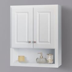 a bathroom with white cabinets and soap dispensers on the shelf above it