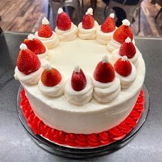 a white cake topped with strawberries on top of a red plate