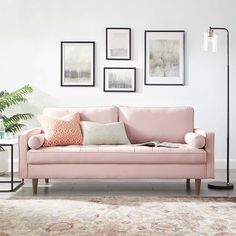 a living room with pink couches and pictures on the wall above it, along with a rug