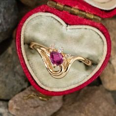 an open heart shaped box with a ring in it