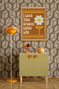 an orange vase sitting on top of a wooden cabinet next to a wall mounted poster